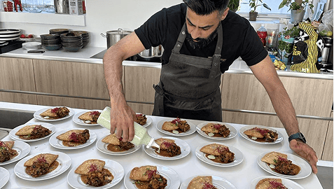 Abdul Manan anretter flere tallerkener med indisk mad